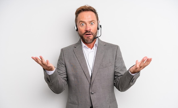 Middle age handsome man feeling extremely shocked and surprised. telemarketing concept