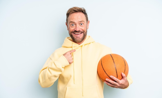 Middle age handsome man feeling happy and pointing to self with an excited. basketball concept