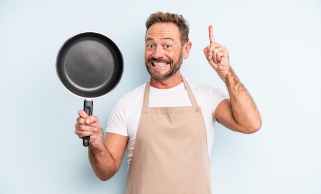 Middle age handsome man feeling like a happy and excited genius after realizing an idea. frying pan concept