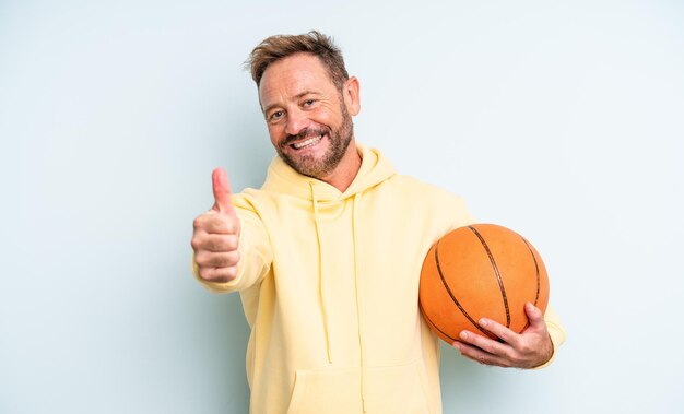 Middle age handsome man feeling proudsmiling positively with thumbs up basketball concept