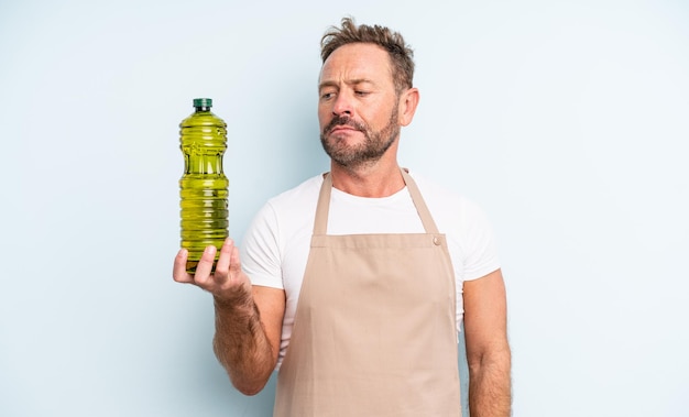 Middle age handsome man feeling sad, upset or angry and looking to the side. olive oil concept