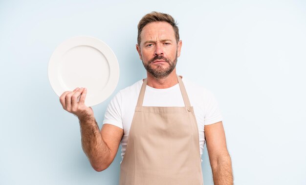 Middle age handsome man feeling sad and whiney with an unhappy look and crying. empty dish concept