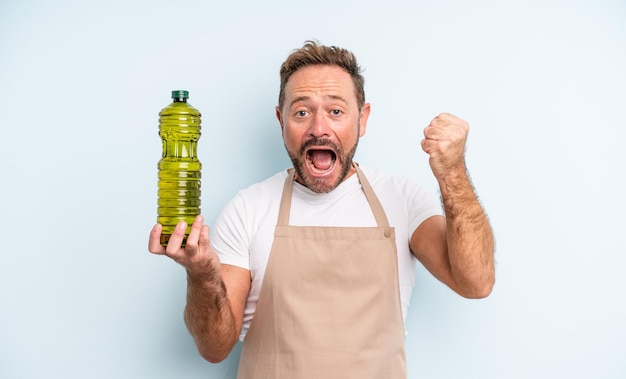 Middle age handsome man feeling shocked,laughing and celebrating success. olive oil concept