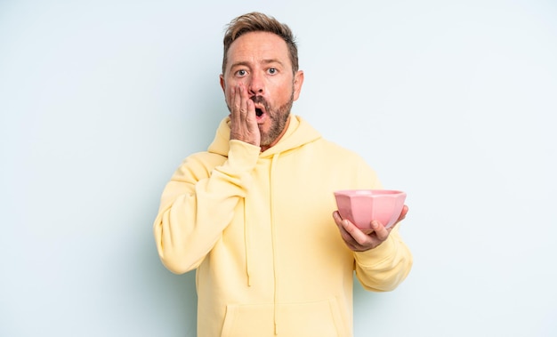 Middle age handsome man feeling shocked and scared. empty bowl concept