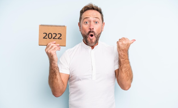 Foto uomo bello di mezza età che sembra stupito per l'incredulità. concetto di calendario 2022