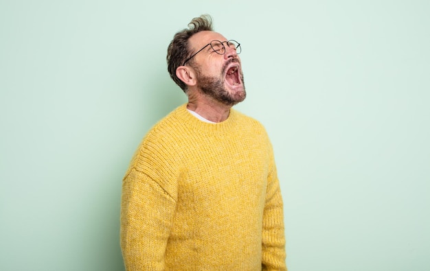 Photo middle age handsome man screaming furiously, shouting aggressively, looking stressed and angry