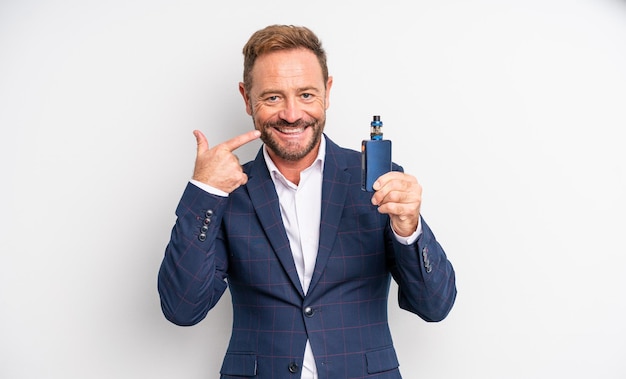 Middle age handsome man smiling confidently pointing to own broad smile smoking vaporizer concept