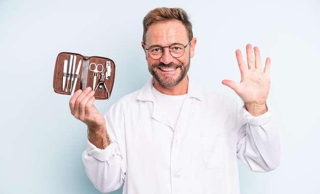 Middle age handsome man smiling and looking friendly, showing number five.  podiatrist concept