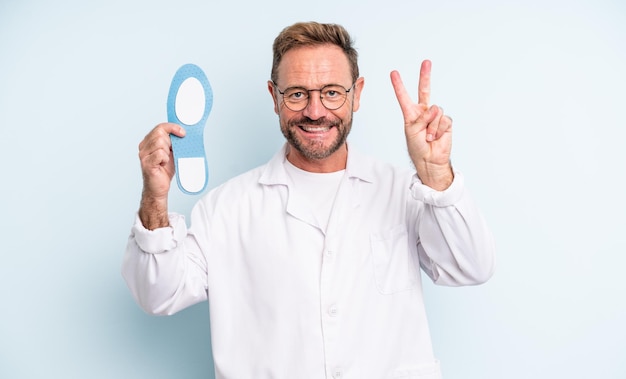 Middle age handsome man smiling and looking friendly showing number two  podiatrist concept