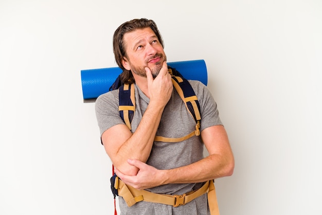 Middle age hiker dutch man isolated on white background looking sideways with doubtful and skeptical expression.