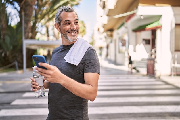 Middle age hispanic man wearing sportswear using smartphone at street