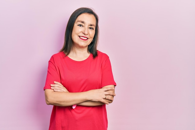 Middle age hispanic woman wearing casual clothes happy face smiling with crossed arms looking at the camera. positive person.