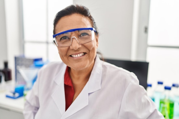 Photo middle age hispanic woman wearing scientist uniform working at laboratory