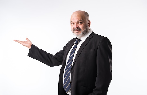 Middle age Indian asian businessman with beard wearing elegant black suit and pointing with hand and finger. presenting product, service or copy space