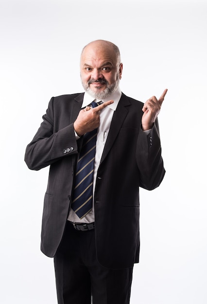 Middle age Indian asian businessman with beard wearing elegant black suit and pointing with hand and finger. presenting product, service or copy space