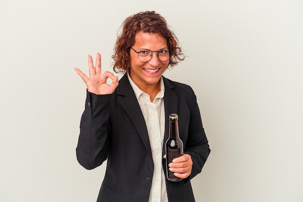 Middle age latin business woman holding a beer isolated on white background cheerful and confident showing ok gesture.