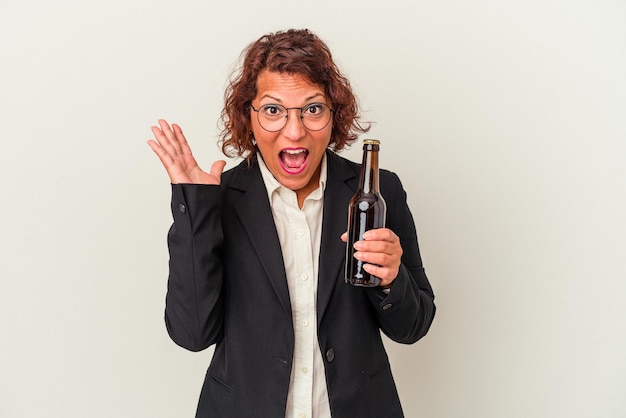 Middle age latin business woman holding a beer isolated on white background surprised and shocked.