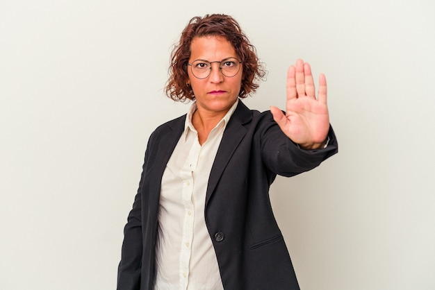 사진 흰색 배경에 격리된 중년 라틴 비즈니스 여성은 손을 뻗은 채 정지 신호를 표시하고 당신을 방해합니다.