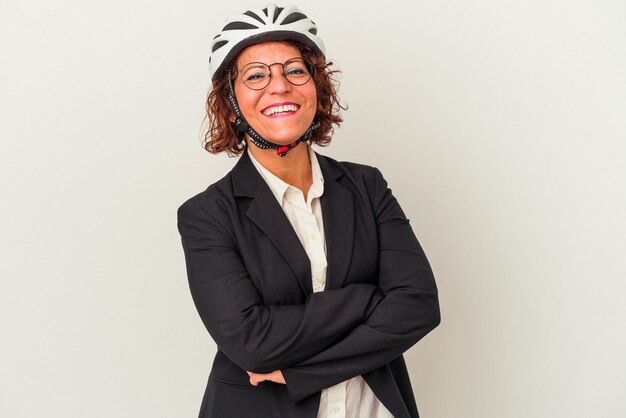 Donna d'affari latina di mezza età che indossa un casco da bici isolato su sfondo bianco ridendo e divertendosi.