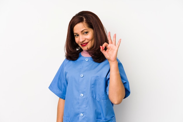 Middle age latin nurse woman isolated ÃÂ§cheerful and confident showing ok gesture.