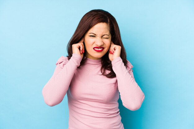 Middle age latin woman isolated covering ears with hands.