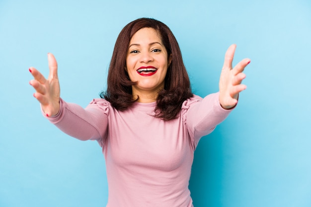 Middle age latin woman isolated feels confident giving a hug to the camera.