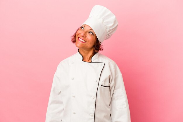 Middle age latin woman isolated on pink background dreaming of achieving goals and purposes