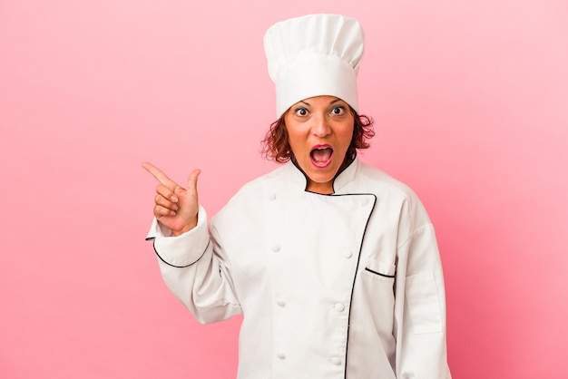 Middle age latin woman isolated on pink background pointing to the side