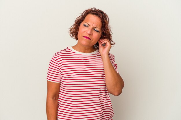 Middle age latin woman isolated on white background covering ears with fingers, stressed and desperate by a loudly ambient.