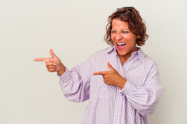 Middle age latin woman isolated on white background pointing with forefingers to a copy space, expressing excitement and desire.