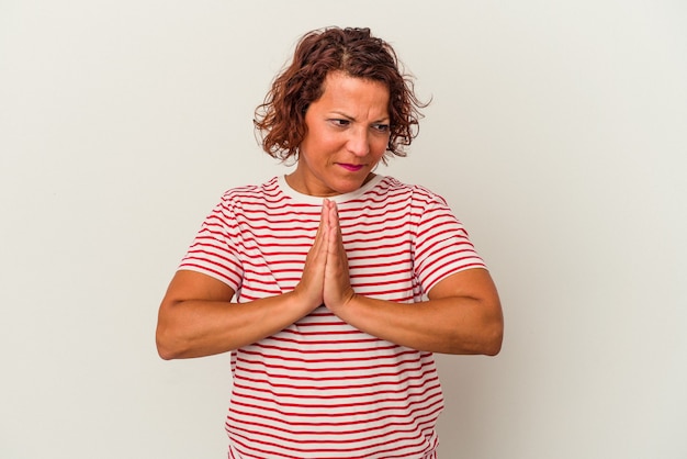 Middle age latin woman isolated on white background praying, showing devotion, religious person looking for divine inspiration.