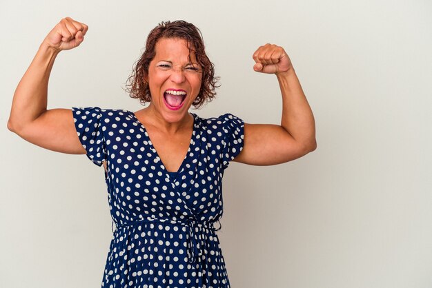 Middle age latin woman isolated on white background raising fist after a victory, winner concept.