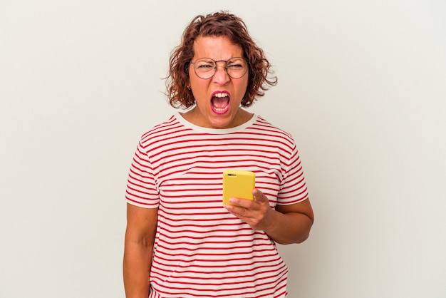 Middle age latin woman isolated on white background screaming very angry and aggressive.