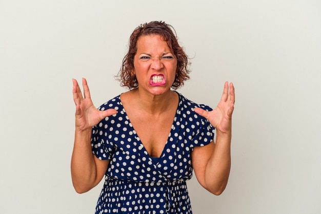 Middle age latin woman isolated on white background screaming with rage.
