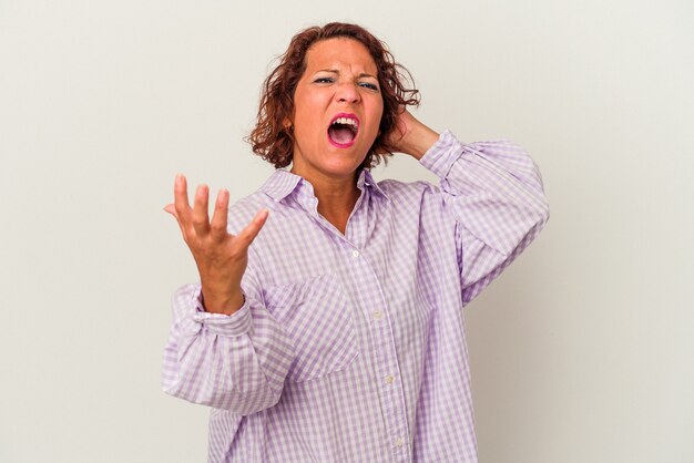 Middle age latin woman isolated on white background screaming with rage.