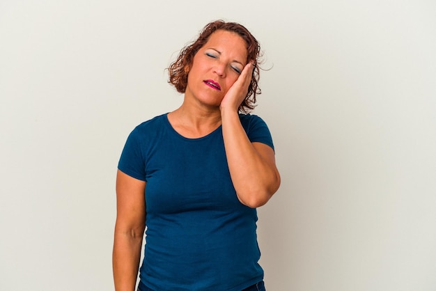 Middle age latin woman isolated on white background tired and very sleepy keeping hand on head.