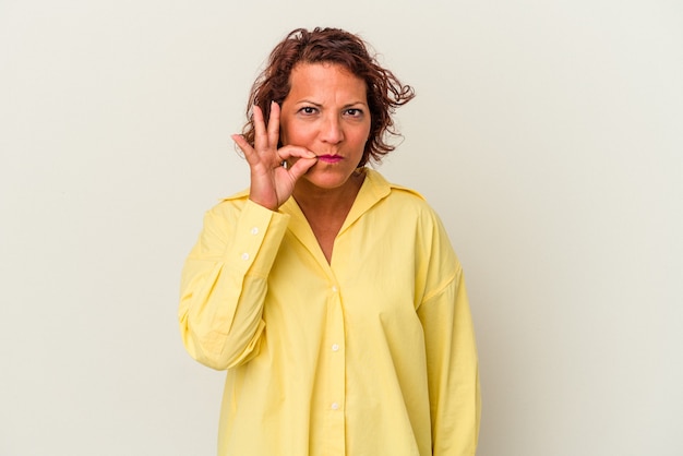 Middle age latin woman isolated on white background with fingers on lips keeping a secret.