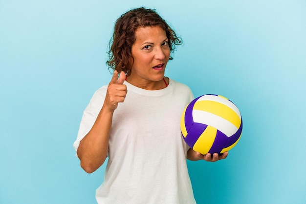 Middle age latin woman playing volleyball isolated on blue background having an idea, inspiration concept.