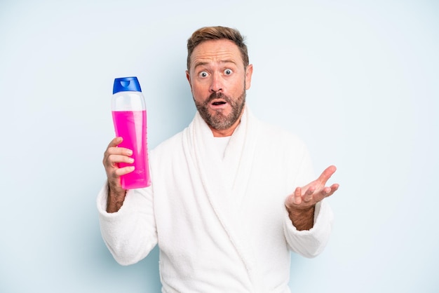 Middle age man amazed, shocked and astonished with an unbelievable surprise. shampoo bottle