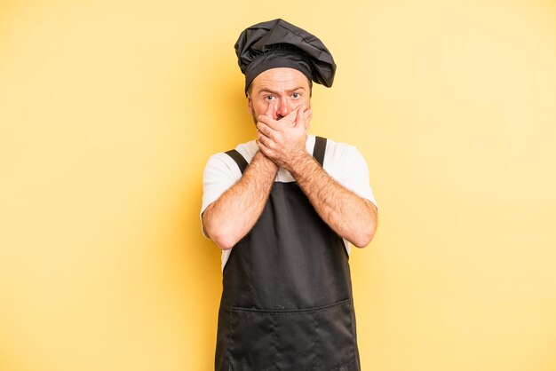 Foto uomo di mezza età che copre la bocca con le mani con un concetto di chef scioccato