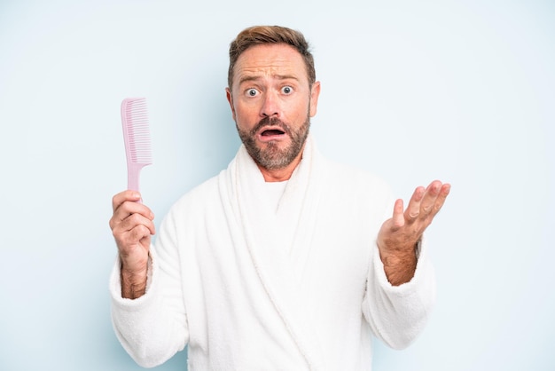 Middle age man feeling extremely shocked and surprised. hair comb concept