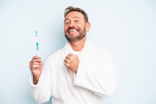 幸せを感じ、挑戦や祝いに直面している中年の男性。歯ブラシのコンセプト
