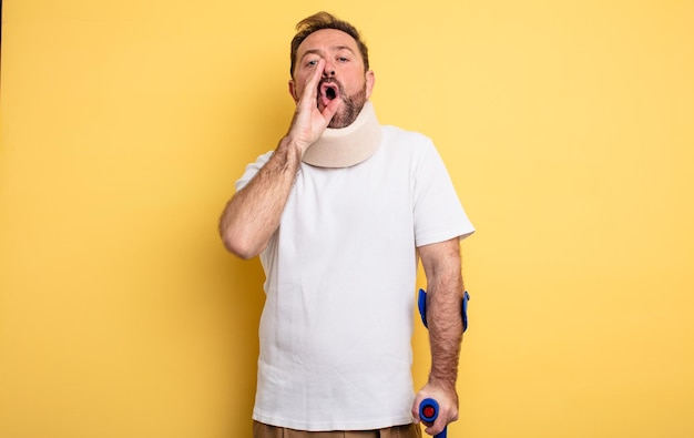 Middle age man feeling happy,giving a big shout out with hands next to mouth accident injured concept