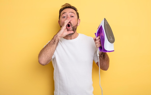 Middle age man feeling happy,giving a big shout out with hands next to mouth. clothes iron concept