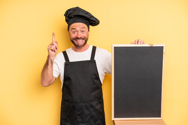 Middle age man feeling like a happy and excited genius after realizing an idea chef and blackboard concept