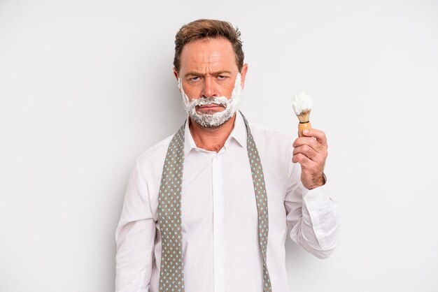 Middle age man feeling puzzled and confused shaving brush and foam concept