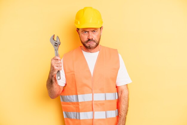 Middle age man feeling sad and whiney with an unhappy look and crying breakdown car repair wrench concept