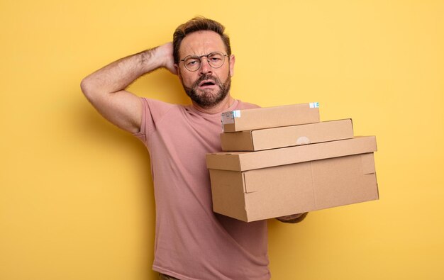 middle age man feeling stressed, anxious or scared, with hands on head. packages boxes concept