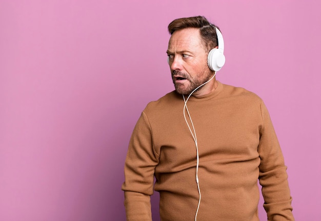 Middle age man listening music with his headphones sport coach concept with a soccer ball