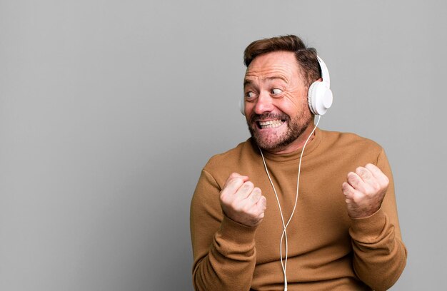 Middle age man listening music with his headphones sport coach concept with a soccer ball